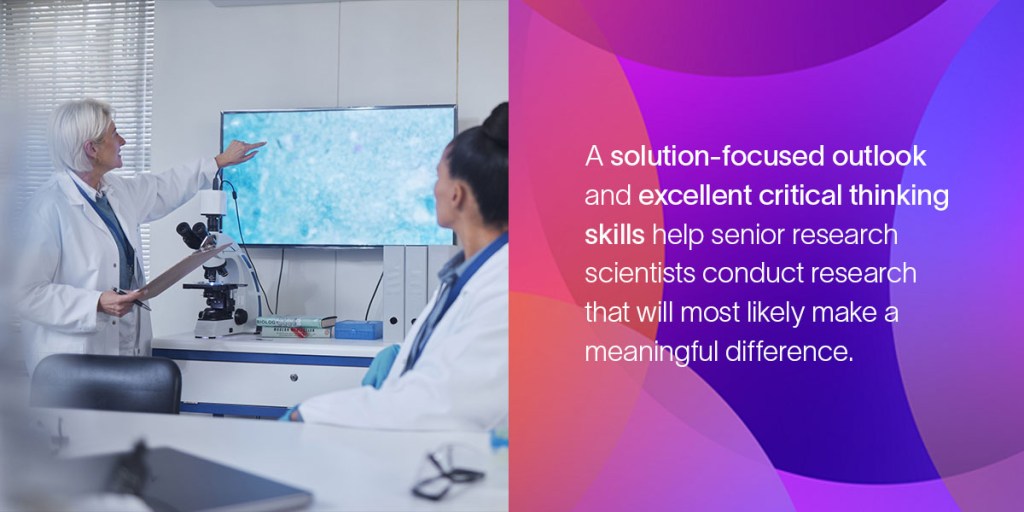 A woman in a lab coat points at research findings displayed on a TV in a classroom