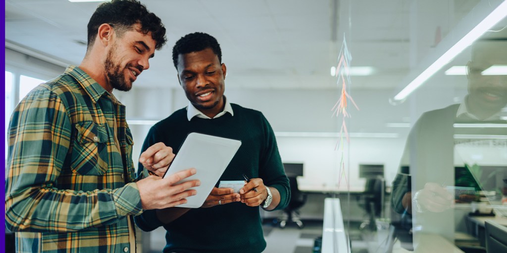 Two men look at a piece of paper while one of the men takes notes