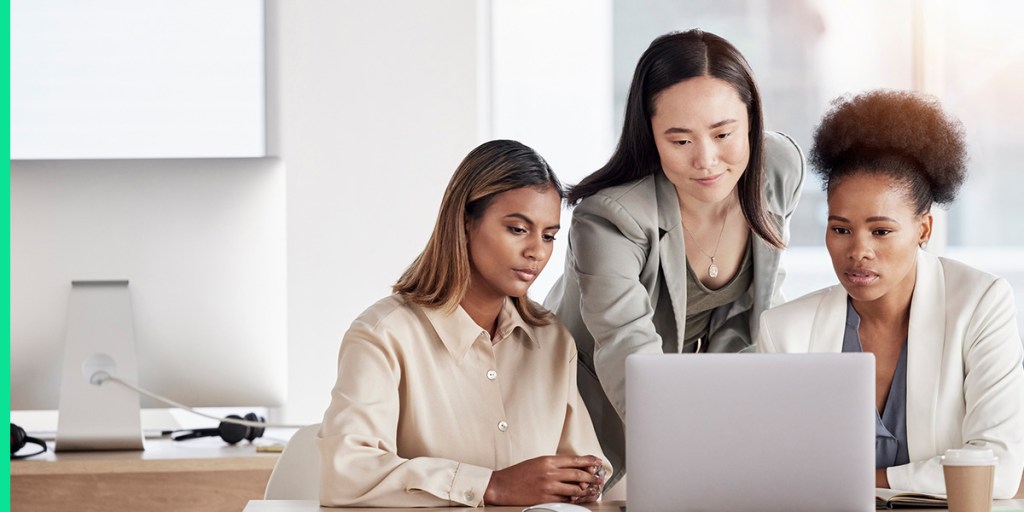 Three business professionals examine a job posting on a laptop