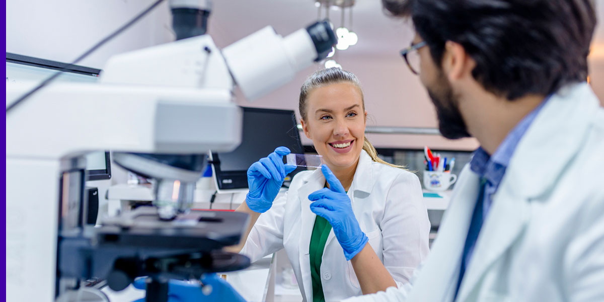 A professional in a research lab holds a microscope slide
