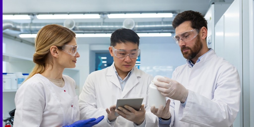 Three life scientists review a bottle in a lab