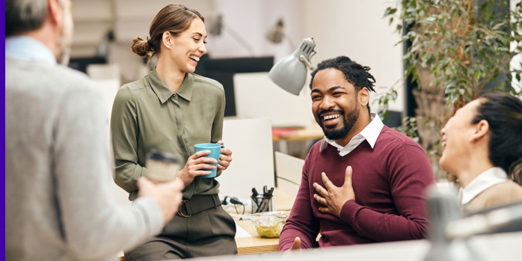 A group of employees smile while talking at the office