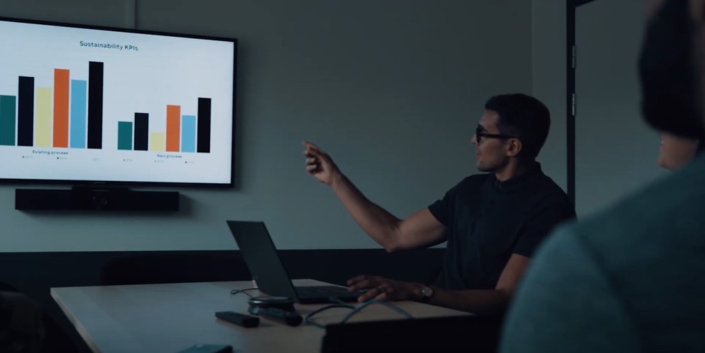 man sitting in darkened room presenting screen with multiple graphs