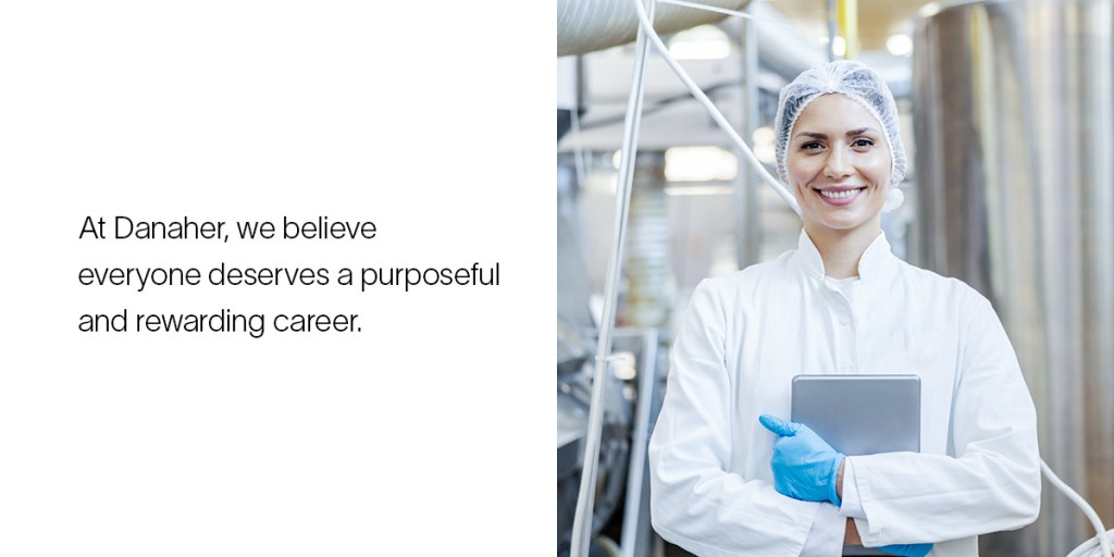 A production engineer holding a clipboard smiles