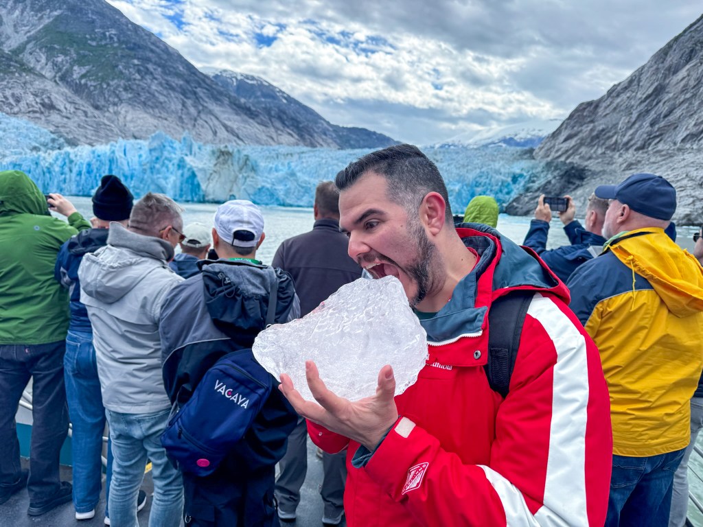 Oliver holding a large chunk of ice, posed with his mouth open to take a bite of it
