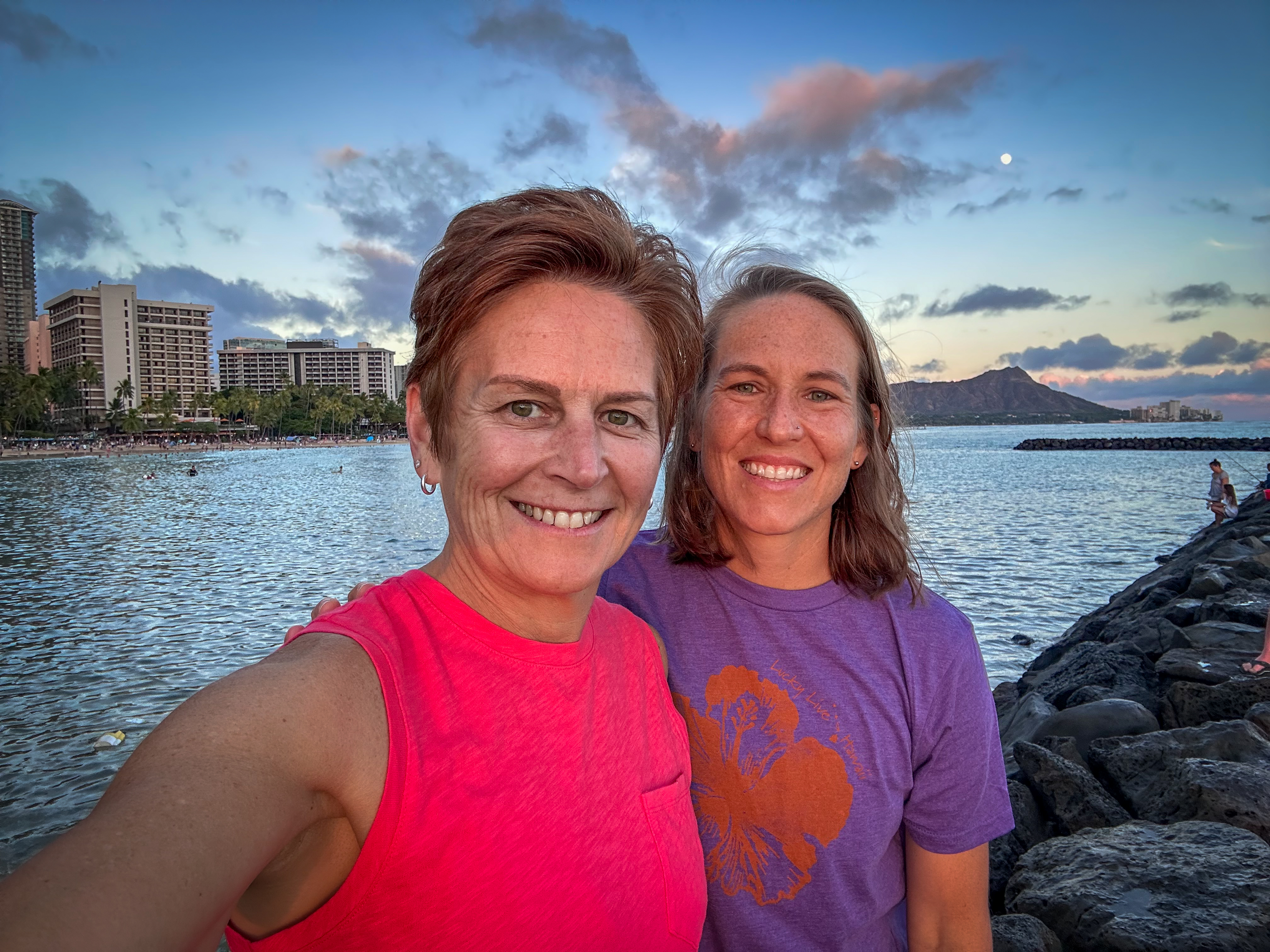 Jessica and her wife posed for a selfie in front of a body of water with buildings in the background