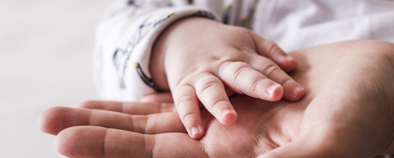 Close up of 4 month old baby boy hand on mother hand.