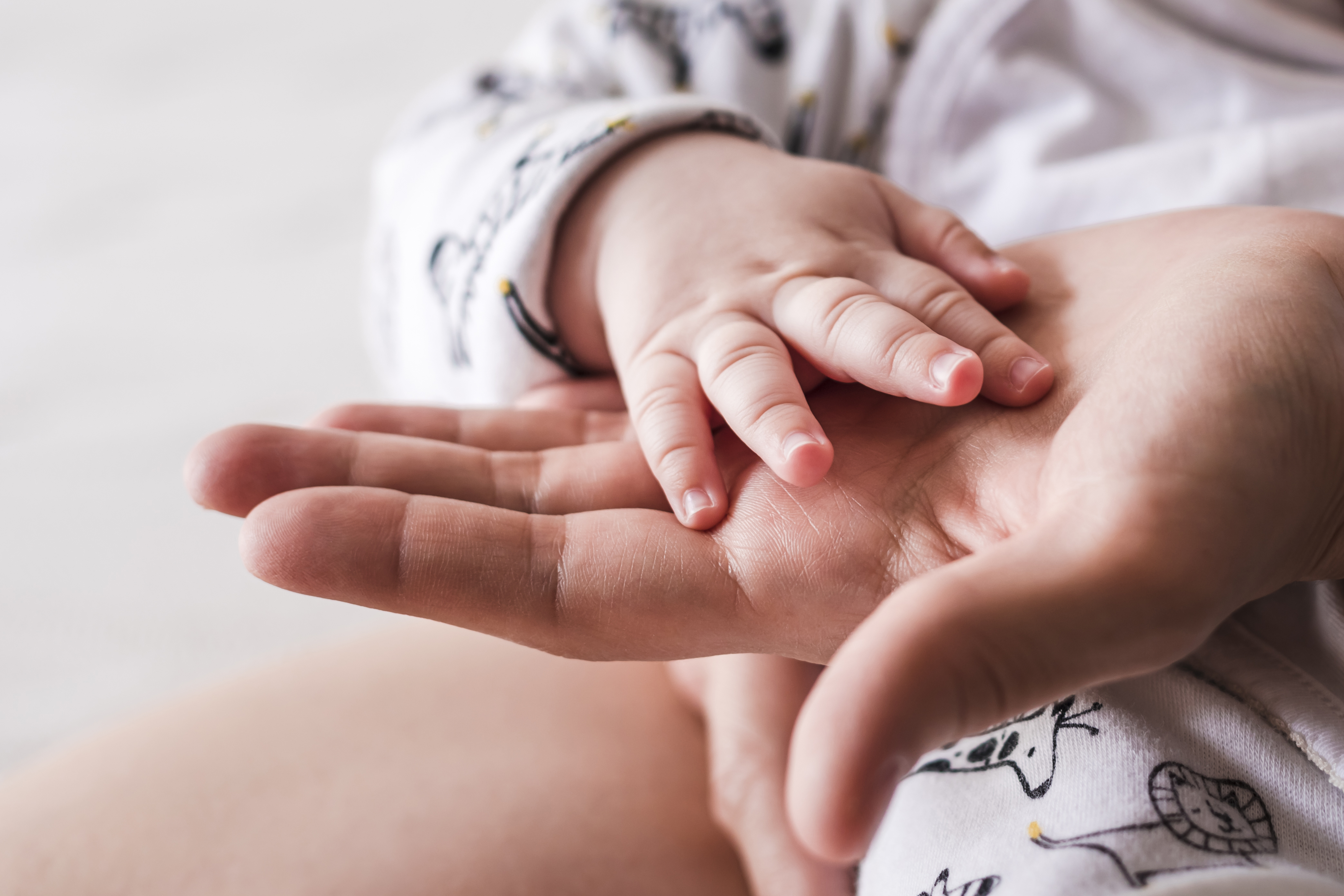 Close up of 4 month old baby boy hand on mother hand.